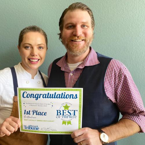 A chef and a man proudly hold a "Best of the Best" award certificate for a locally owned restaurant.