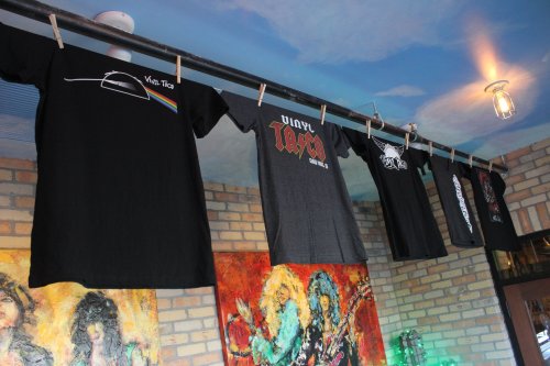 A row of black t-shirts hanging on a clothesline, featuring various graphic designs and logos.