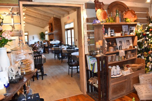 Cozy restaurant interior with wooden decor, tables set for dining, and a display shelf filled with various items.
