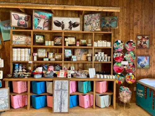 A rustic wooden display filled with various handmade crafts, jars, and colorful baskets in a cozy shop setting.