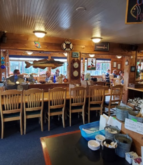 A cozy restaurant interior with wooden decor, tables, and patrons enjoying their meals.
