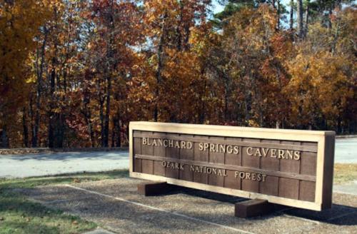Sign for Blanchard Springs Caverns in Ozark National Forest, surrounded by colorful autumn foliage.