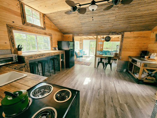 Cozy wooden kitchen with modern appliances, a dining area, and large windows letting in natural light.