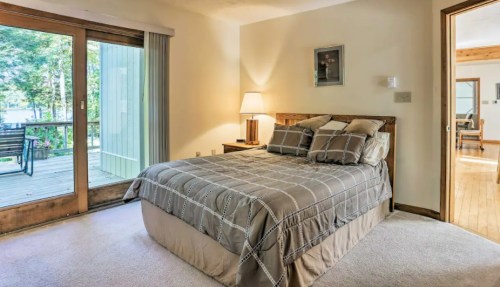 Cozy bedroom with a queen bed, soft lighting, and sliding glass doors leading to a deck.