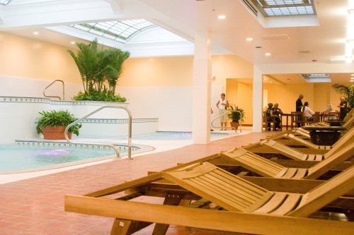 A serene indoor spa area with lounge chairs, a hot tub, and tropical plants, featuring soft lighting and a relaxing atmosphere.
