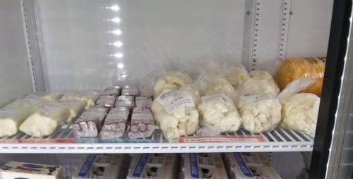 A refrigerated display showcasing various packaged cheese products and blocks, neatly arranged on shelves.