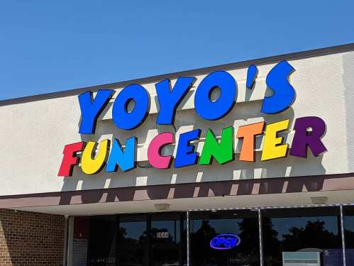 Colorful sign for "Yoyo's Fun Center" on a building, with a bright blue sky in the background.