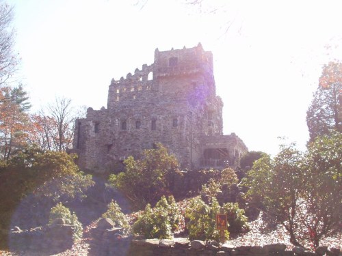 A stone castle surrounded by trees and colorful foliage, illuminated by bright sunlight.