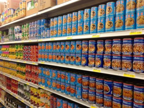 A grocery store aisle filled with colorful canned goods on shelves, showcasing various brands and types of food.