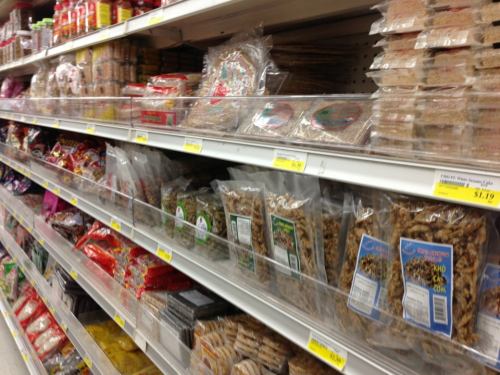 A grocery store aisle filled with various packaged snacks and food items on shelves.