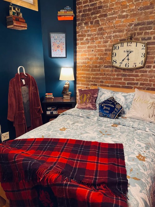 Cozy bedroom with a brick wall, a bed with decorative pillows, a clock, and a warm blanket draped over the edge.