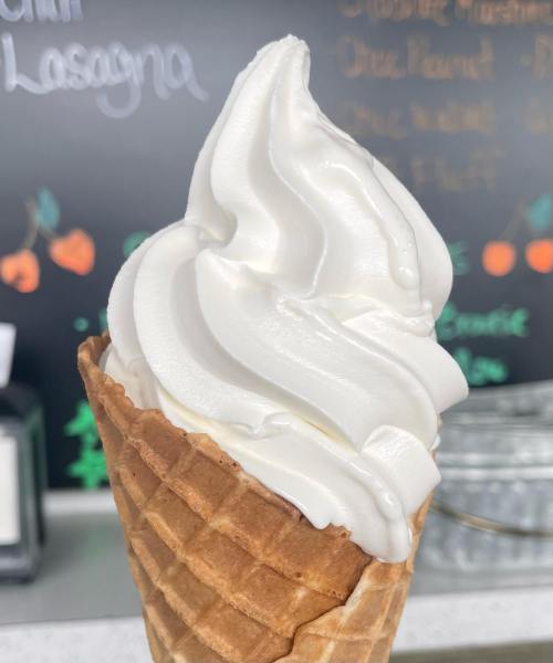 A close-up of a soft-serve ice cream cone with a swirl of creamy white ice cream on a waffle cone.