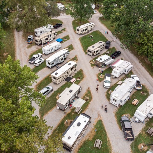 Aerial view of a campground with several RVs parked along gravel paths and people walking around.