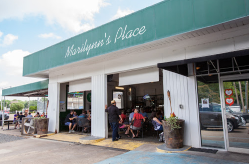 Exterior of Marilyn's Place, a casual eatery with outdoor seating and patrons enjoying their meals on a sunny day.