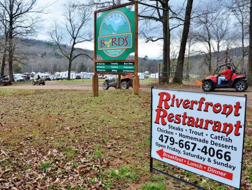 Signage for Byrd's Adventure Center and Riverfront Restaurant, surrounded by trees and recreational vehicles.