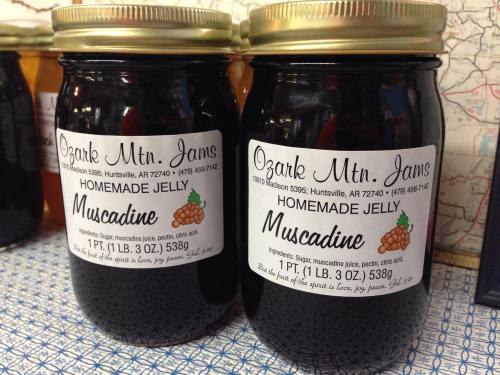 Two jars of Ozark Mountain Jams Muscadine Jelly, labeled with ingredients and weight, on a patterned surface.