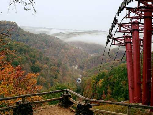 A scenic view of misty mountains and autumn foliage, with a cable car structure in the foreground.