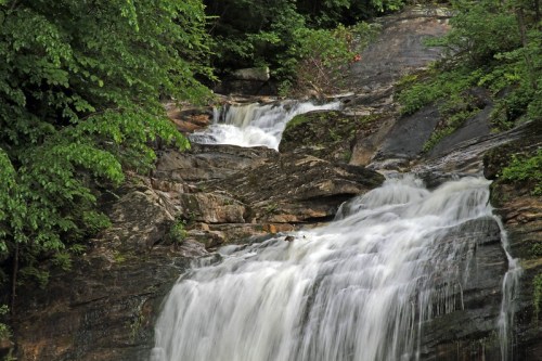 A serene waterfall cascading over rocky terrain, surrounded by lush green foliage.