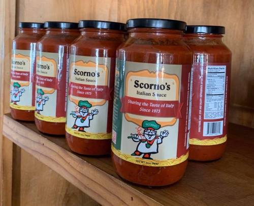 Five jars of Scorno's Italian Sauce lined up on a wooden shelf, showcasing the label and nutrition information.