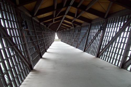 A long, narrow corridor with large windows and a wooden ceiling, creating a geometric perspective.