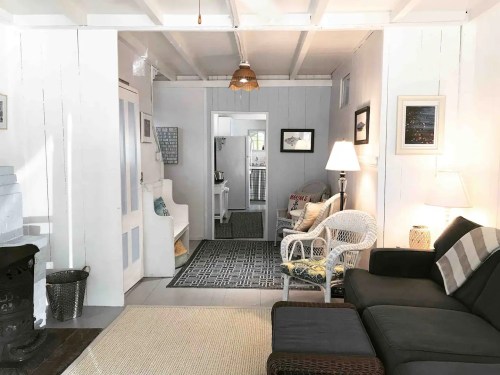 Cozy interior of a home featuring a living area with a sofa, chairs, and a view into a kitchen area.
