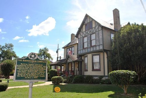 Historic Birnheimer Complex, a Victorian-style house with a sign, surrounded by greenery and blue skies.