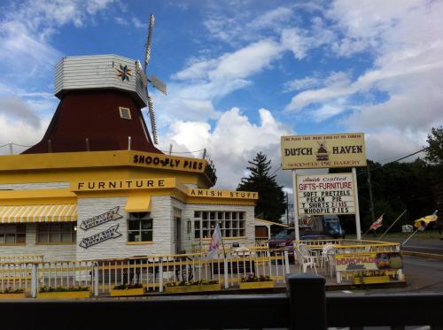 A whimsical building with a windmill, featuring signs for Dutch Haven, Snoopy Pies, and Amish crafts in a scenic setting.