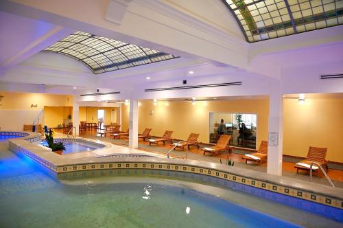 Indoor spa area featuring a pool, lounge chairs, and a glass ceiling with soft lighting.