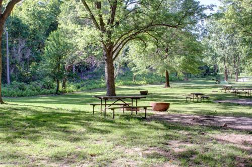 A serene park scene with green grass, trees, and picnic tables under a clear sky.