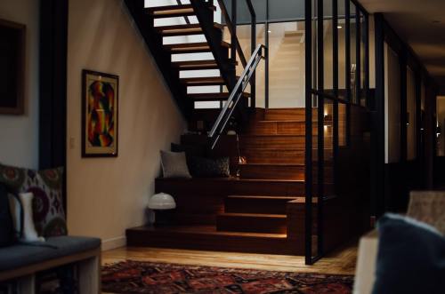 A modern staircase with wooden steps, surrounded by glass walls and soft lighting, in a stylish interior setting.