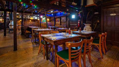 Cozy restaurant interior with wooden tables, chairs, and colorful lights, creating a warm, inviting atmosphere.