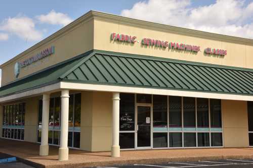 Exterior of a store featuring a green roof and signage for fabric and sewing machines.