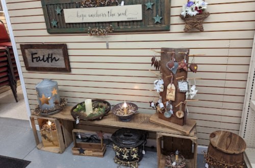 A display of rustic home decor items, including candles, wooden signs, and decorative accents on shelves.