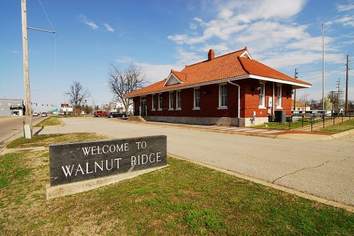 A brick building with a red roof and a sign reading "Welcome to Walnut Ridge" in a grassy area.