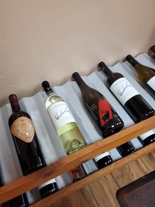 A wooden wine rack displaying several bottles of wine with various labels and colors.