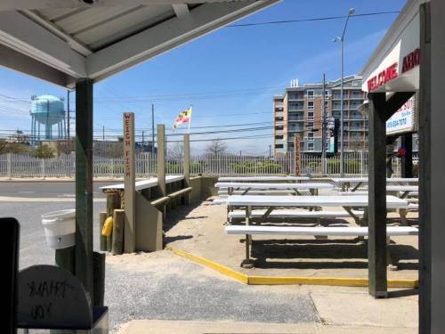 View of an outdoor seating area with picnic tables, a water tower in the background, and a clear blue sky.
