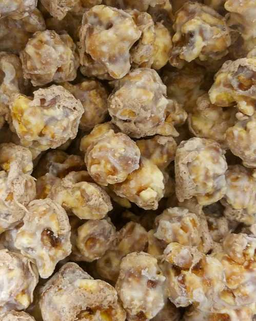 A close-up of caramel-coated popcorn clusters, showcasing a mix of light and dark brown textures.