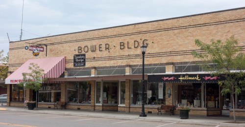 Exterior view of Bower Building featuring shops, awnings, and a cloudy sky above.