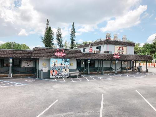A restaurant building with a mural, surrounded by parking spaces and trees under a partly cloudy sky.