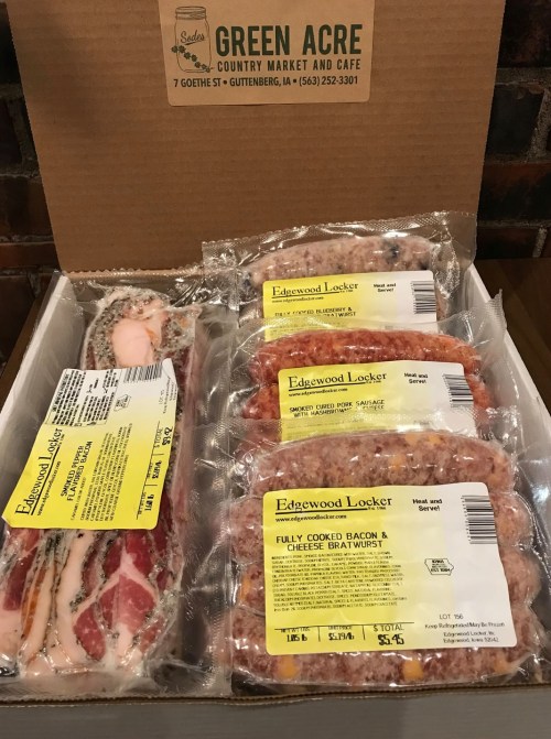 A box containing various meat products, including fully cooked bacon and cheese bratwurst, with labels visible.