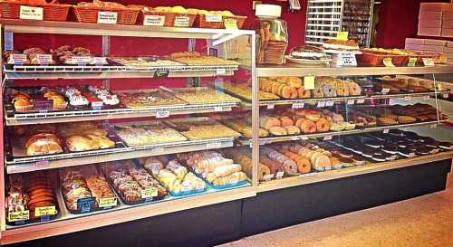 A display case filled with a variety of baked goods, including pastries, donuts, and cookies.