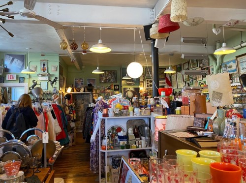 A cozy vintage shop filled with colorful clothing, decor, and various eclectic items on display.