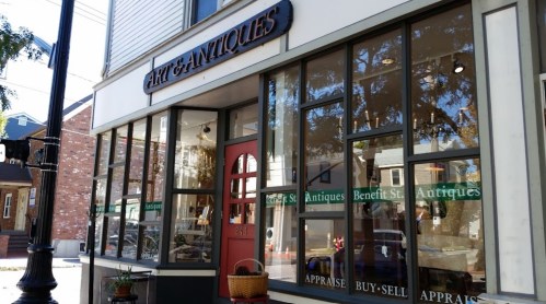 A storefront labeled "Art & Antiques" with large windows displaying various antique items inside.