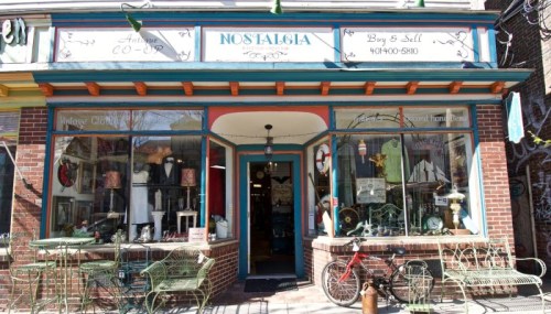 A vintage shop named "Nostalgia" with a colorful facade, displaying antiques and a bicycle outside.
