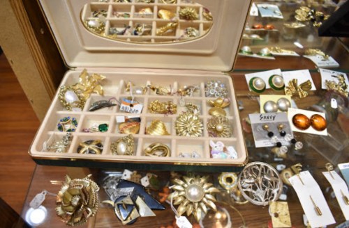 A display of vintage jewelry in a case, featuring various brooches, earrings, and decorative pieces.