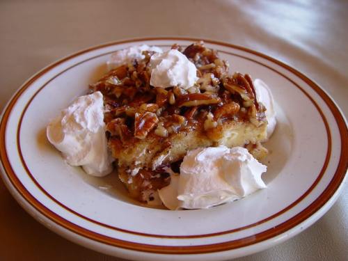 A slice of pecan pie topped with whipped cream on a plate.