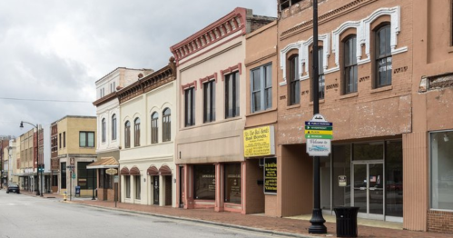 A row of historic buildings on a quiet street, featuring various architectural styles and storefronts.