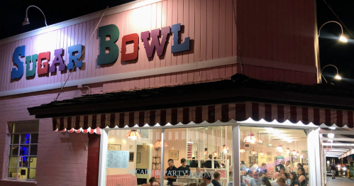A brightly lit restaurant named "Sugar Bowl" with people dining inside, featuring colorful signage and a cozy atmosphere.