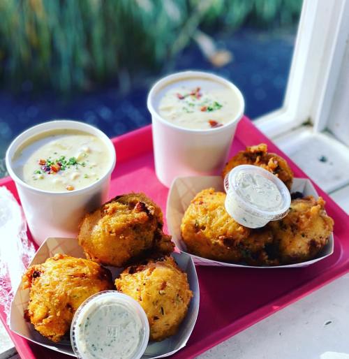 Two cups of creamy soup and two trays of golden-brown fritters with dipping sauce, served on a red tray.