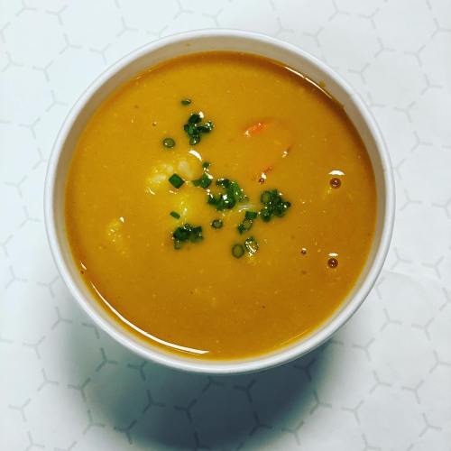 A bowl of creamy soup topped with chopped green onions, set against a patterned background.